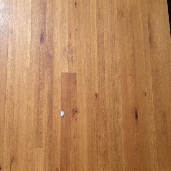 A wooden dining table with white water rings and scratches before restoration.